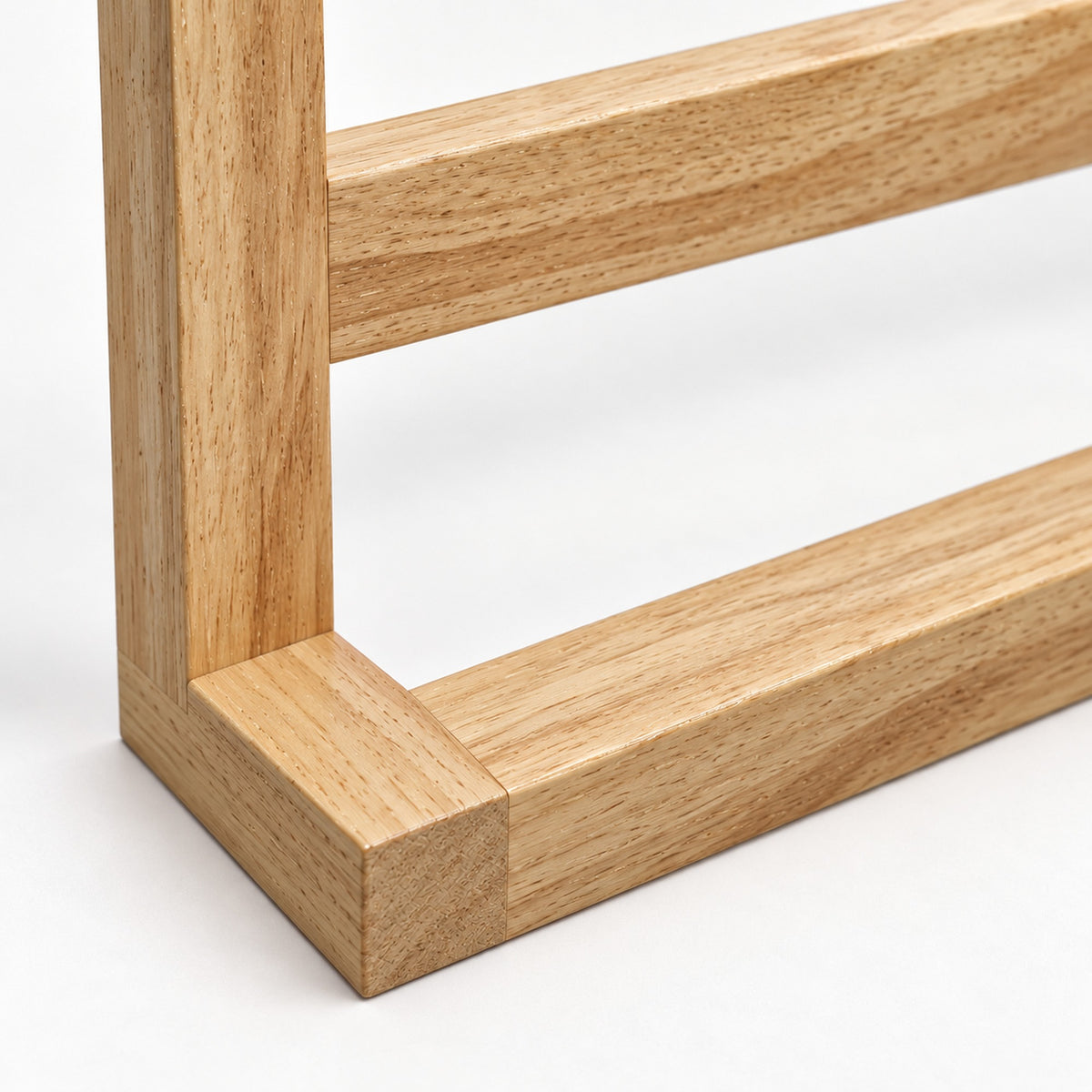 Nahaufnahme der Kautschukholzmaserung und der rechtwinkligen Holzverbindung am Handtuchhalter.
